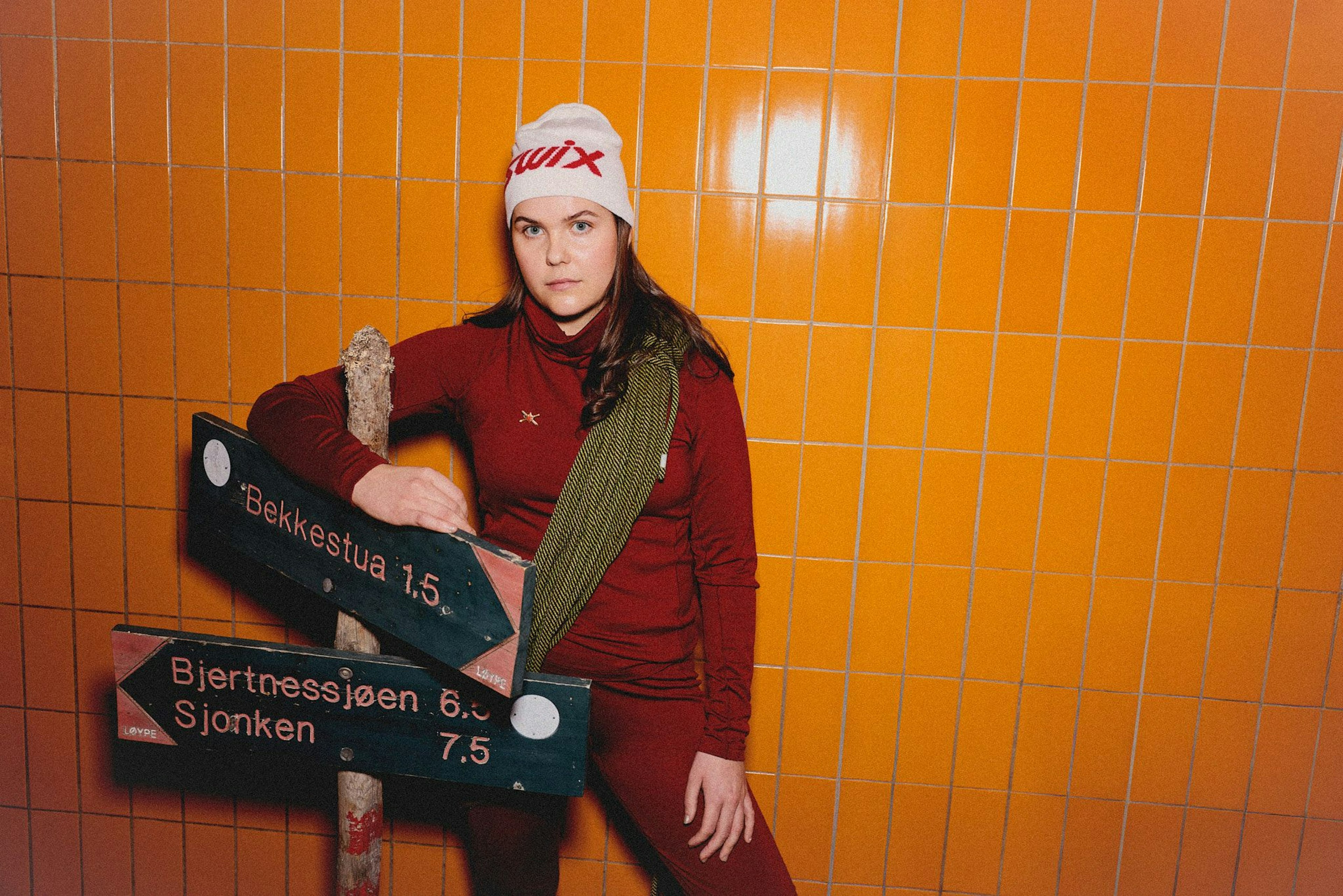 Tiril som lener seg mot en skiltstake