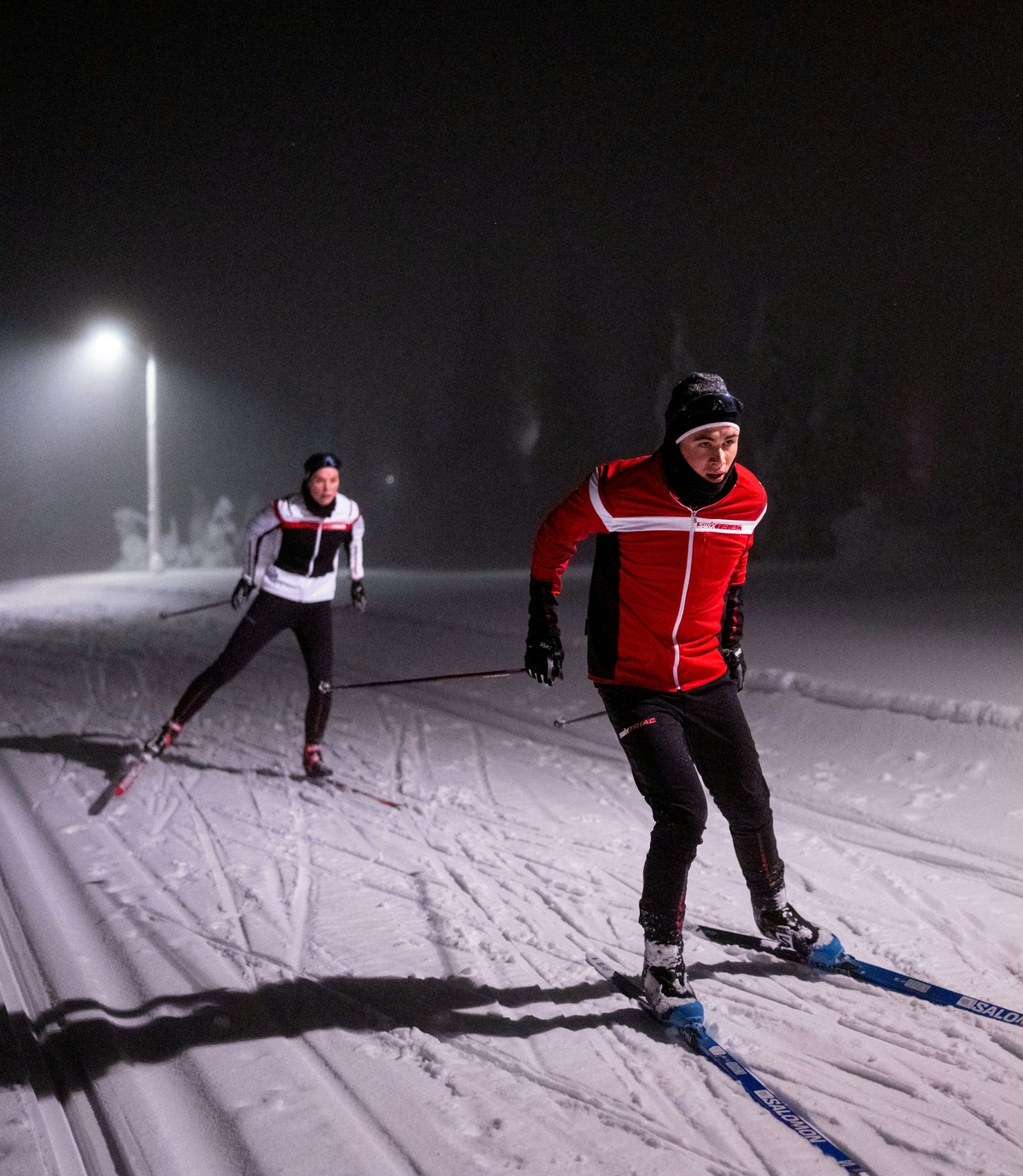 Mann og dame går på ski om kvelden
