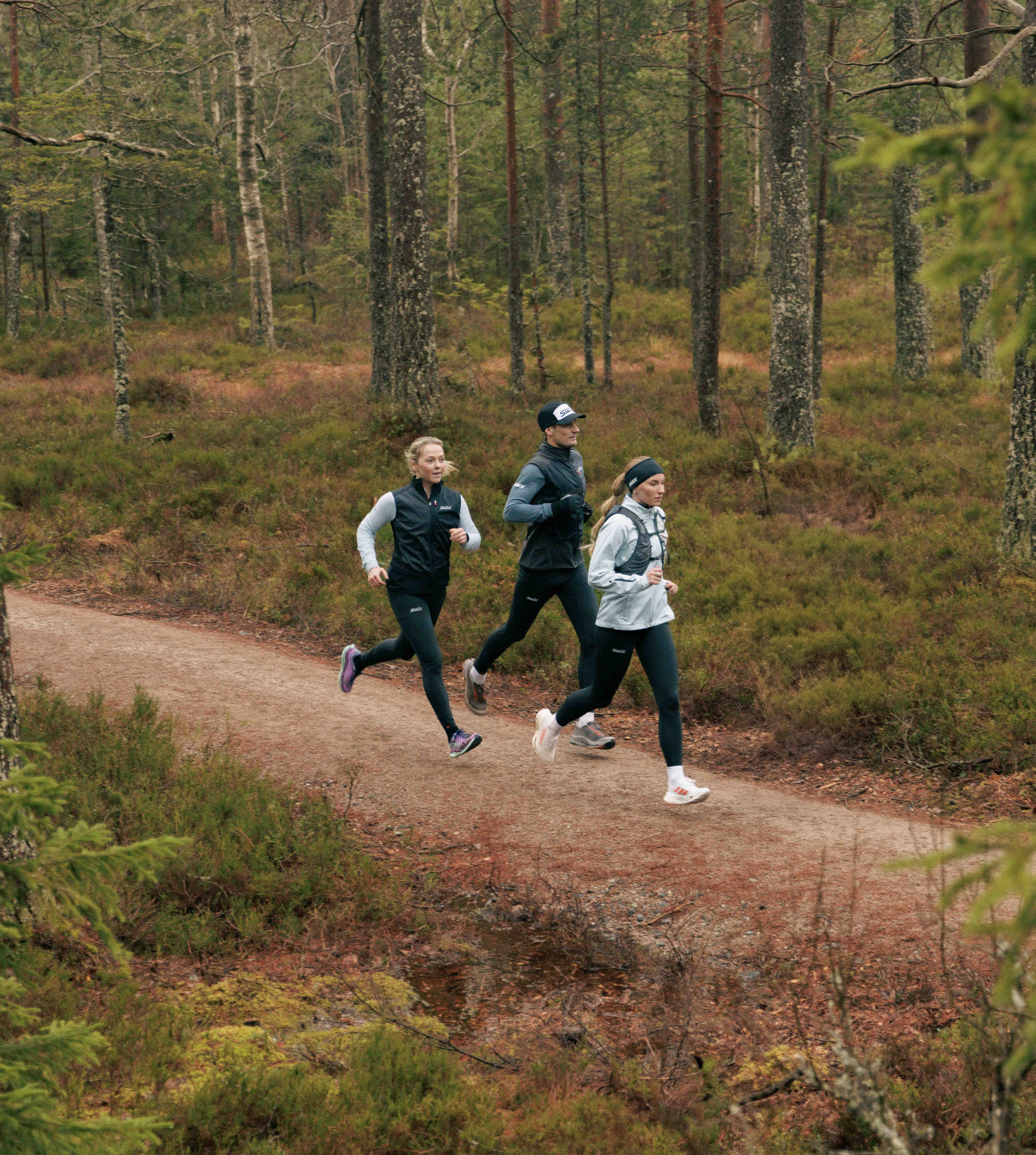 three persons running in the forest